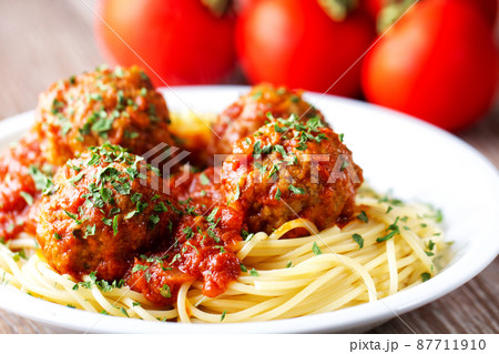 Spaghetti pasta with meatballs in tomato sauce and herbs on a white plate. 87711910