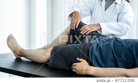 Female physiotherapist doing healing treatment and rehabilitation injured knee of patient by stretching 87712200