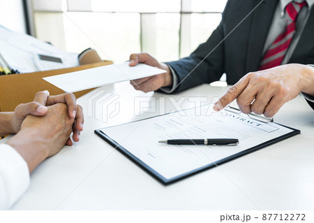 Close up of the hand employer focus the employee to write a letter of resignation and filing final remuneration, resign concept Close up of the hand employer focus the employee to write a letter of resignation and filing final remuneration, resign concept 87712272
