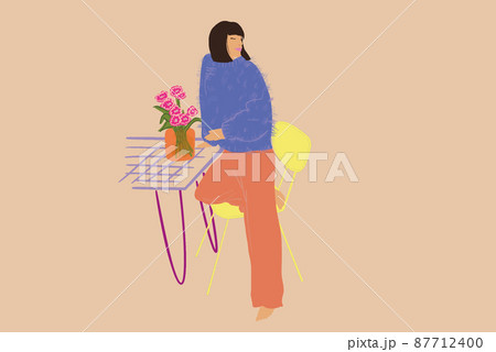 Beautiful stylish woman standing relaxed by the table with vase of flowers 87712400