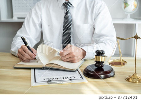 Male lawyer or jurist working with litigation contract paper documents of the estate lawsuit, Law books and wooden gavel on table in office 87712401
