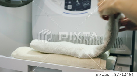 Close up of young woman folds towels after washing in laundry room. 87712464