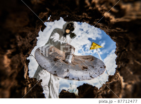 View from earth pit. Selective focus on shovel equipment using during ecological experiment in radioactive dangerous environment, blurred male scientist have biological research in nuclear area. 87712477