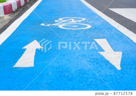Blue bicycle lane on road with white bicycle icon and arrow. Empty Bicycle way for bike. Blue bicycle lane on road with white bicycle icon and arrow. Empty Bicycle way for bike. 87712578