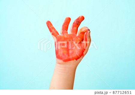 Colourful painted child showing hand fingers sign ok isolated on green background. Close up copy space 87712651