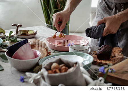 Process of decorating rustic style table with craft plates, linen tableclothe and napkins , gluten free pastry and wild berries 87713358
