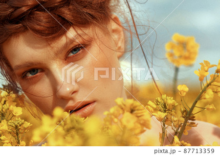Young fashion model portrait with ginger hair and blue eyes in yellow rapeseed field. Spring concept 87713359