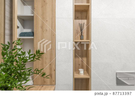 Modern minimalist bathroom interior design with ecru stone tiles and wood wall hidden shelf for bathroom accessories 87713397
