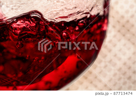 Red wine is poured into a glass. Red wine is poured into a glass. 87713474