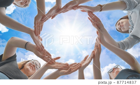 Friends make a circle from their palms against the background of a fabulous sky. Friends make a circle from their palms against the background of a fabulous sky. 87714837