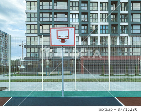 outdoor sports. basketball court in a residential area. ball game next to tall glass houses. basketball hoop on the court. Durable anti-slip rubber for running outdoor sports. basketball court in a residential area. ball game next to tall glass houses. basketball hoop on the court. Durable anti-slip rubber for running 87715230