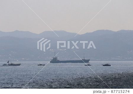 薄雲と山々と街並みの見える島とタンカーと漁船の行き交うキラキラ光る水面と青い海面の海の風景 薄雲と山々と街並みの見える島とタンカーと漁船の行き交うキラキラ光る水面と青い海面の海の風景 87715274