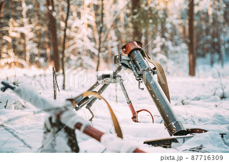German mine-thrower mortar of times of the second world war in snowy winter forest. Wehrmacht weapon. World War II WWII German mine-thrower mortar of times of the second world war in snowy winter forest. Wehrmacht weapon. World War II WWII 87716309