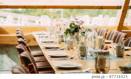 Cozy Interior Of Summer Cafe. Jug Of Icy Cold Ice Water On Table And Cutlery Laid Out Cozy Interior Of Summer Cafe. Jug Of Icy Cold Ice Water On Table And Cutlery Laid Out 87716325