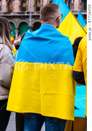 Young man wrapped in the Ukrainian flag in a protest against Russia invasion 87716450