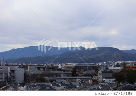 曇り空と山々と市街地の街並みの見える風景 曇り空と山々と市街地の街並みの見える風景 87717198