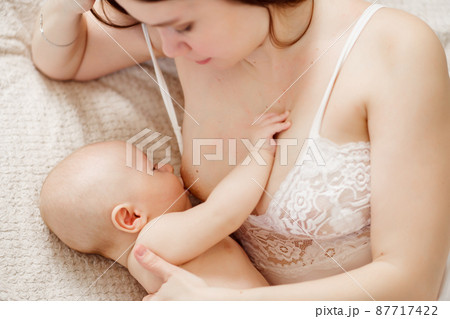 a mother feeds the baby with breast milk on the bed. the breastfeeding. a mother feeds the baby with breast milk on the bed. the breastfeeding. 87717422