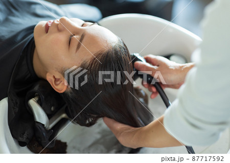 美容室でトリートメントしてもらう女性 87717592