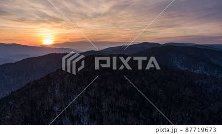 Aerial drone view in mountain forest. Winter landscape. Snowy Fir and Pine trees. Snowy tree branch in a view of the winter forest. Winter landscape, forest, trees covered with frost, snow. 87719673