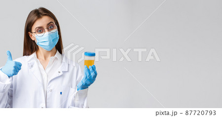 Covid-19, medical research, diagnosis, healthcare workers and quarantine concept. Doctor or clinic lab employee holding patient urine sample, wear medical mask and gloves, thumb-up Covid-19, medical research, diagnosis, healthcare workers and quarantine concept. Doctor or clinic lab employee holding patient urine sample, wear medical mask and gloves, thumb-up 87720793