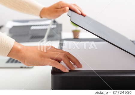 Woman hand putting white paper in printer, scanner,  copy machine, office document, photocopier. 87724950