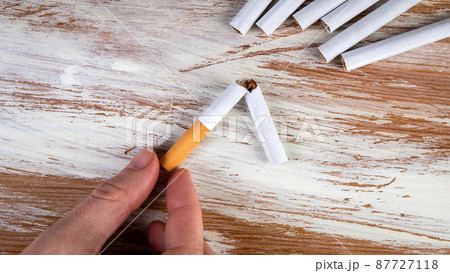 Quit smoking. Broken cigarette on a white painted wooden background 87727118