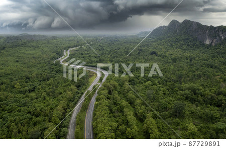 Top view of countryside road passing through the green forrest and mountain 87729891