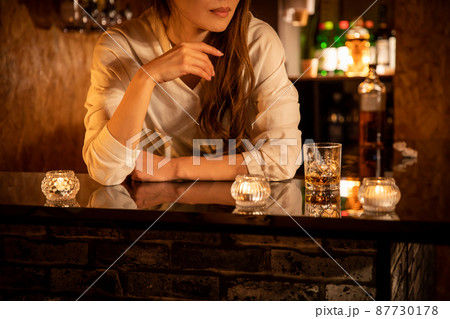 バーカウンターで頬杖をつく女性　BAR 87730178