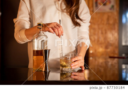 バーカウンターでお酒をつくる女性　BAR 87730184