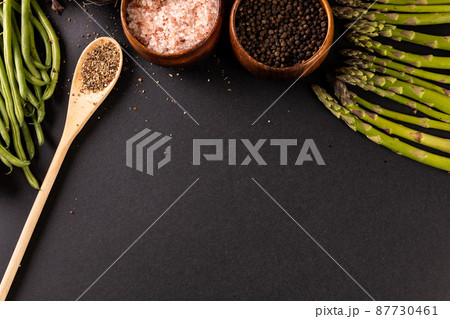 High angle view of spices with asparagus and french beans on black background with copy space 87730461