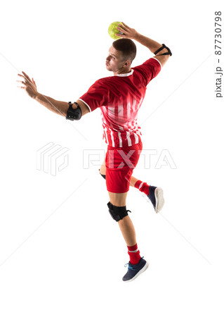 Confident young male caucasian handball player throwing ball against white background 87730798