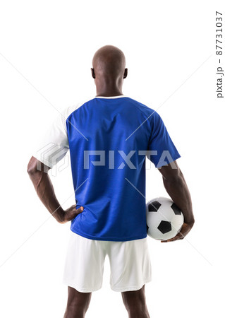Rear view of african american young male soccer player holding ball over white background Rear view of african american young male soccer player holding ball over white background 87731037
