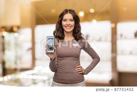 female shop assistant with qr code on smartphone 87731432