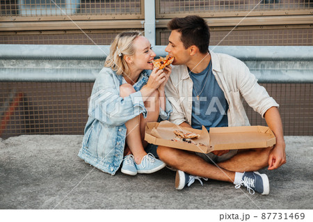 happy couple eating pizza on city roof top parking 87731469