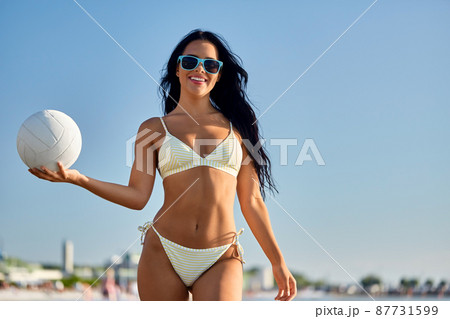 woman in bikini posing with volleyball on beach 87731599