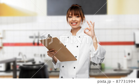 smiling female chef with clipboard showing ok 87731994
