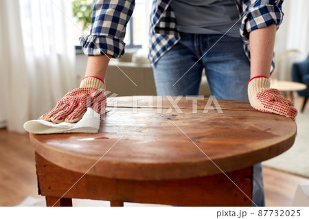 woman cleaning old table surface with paper tissue 87732025