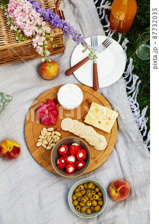 food, drinks and basket on picnic blanket on grass food, drinks and basket on picnic blanket on grass 87732035