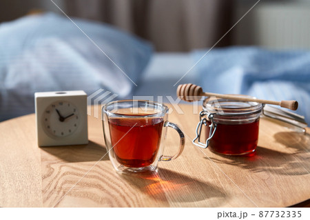 cup of tea, honey and alarm clock on table 87732335