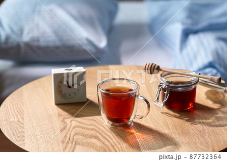 cup of tea, honey and alarm clock on table 87732364