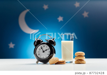 glass of milk, cookies and alarm clock at night glass of milk, cookies and alarm clock at night 87732428
