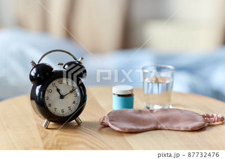 alarm clock, mask and sleeping pills on table alarm clock, mask and sleeping pills on table 87732476