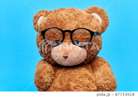 brown teddy bear toy in glasses on blue background brown teddy bear toy in glasses on blue background 87733028