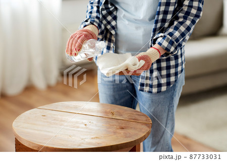 woman degreasing old table surface with solvent 87733031