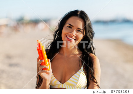 smiling woman in bikini with sunscreen on beach smiling woman in bikini with sunscreen on beach 87733103