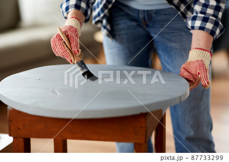 woman painting old wooden table in grey color 87733299