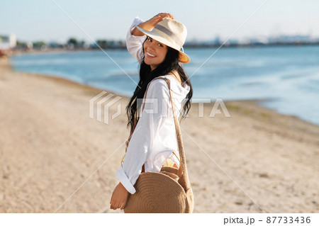 happy woman with bag walking along summer beach happy woman with bag walking along summer beach 87733436