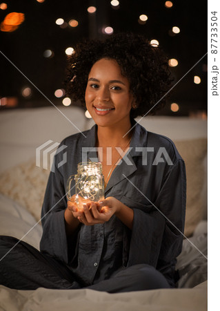 happy woman in pajamas sitting in bed at night happy woman in pajamas sitting in bed at night 87733504