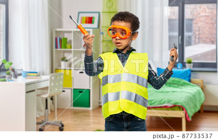 little boy in safety vest with screwdriver at home 87733537