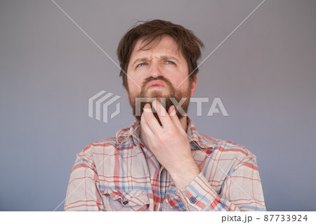 Pensive man with beard has clever expression, looks thoughtfully aside Pensive man with beard has clever expression, looks thoughtfully aside 87733924